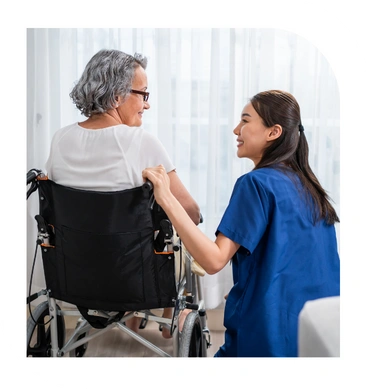 Caregiver assisting a woman in a wheelchair at home during recovery with daily support
